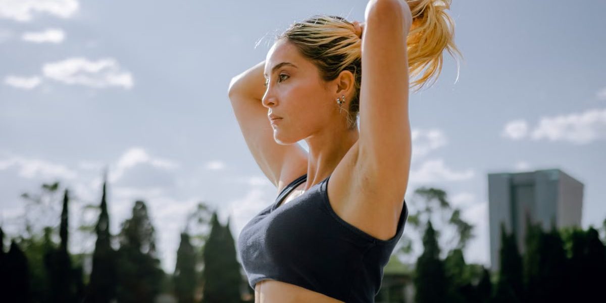 A focused woman in sportswear tying her hair, preparing for an outdoor workout in Mexico City.