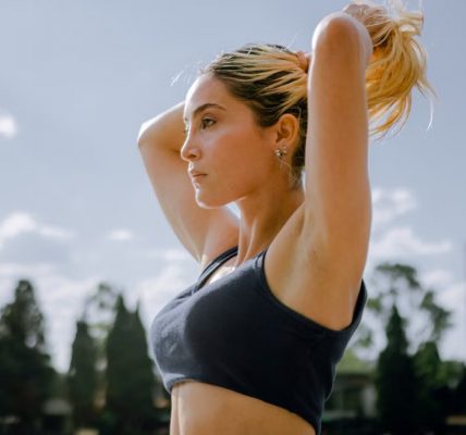 A focused woman in sportswear tying her hair, preparing for an outdoor workout in Mexico City.